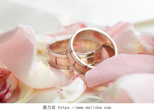放在撒满花瓣的白布上的金戒指金戒指和玫瑰花瓣